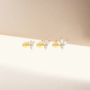 Detailed view of three gold floral stud earrings featuring sparkling clear zircon stones