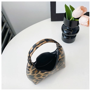 Detailed top view of a glossy patent leather handbag with leopard print and zipper closure