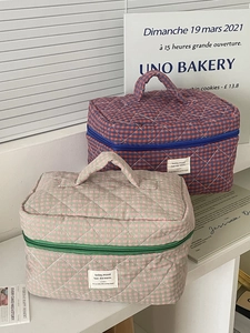 Detail of quilted checkered toiletry bags with top handle and secure zipper closure