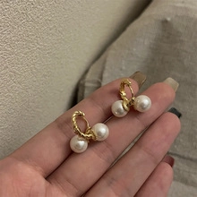 Detailed shot of gold twisted hoop earrings featuring elegant white hanging pearls