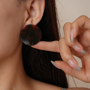 Gros plan d'une boucle d'oreille ronde en acrylique marbré rouge au style vintage