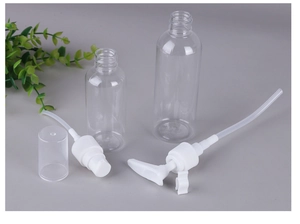 Close-up of clear PET plastic travel bottles with white pump heads and green plant accent