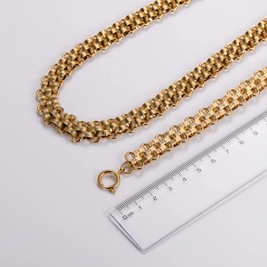 Detailed view of golden multi-strand braided chain necklace with a ruler for size scale