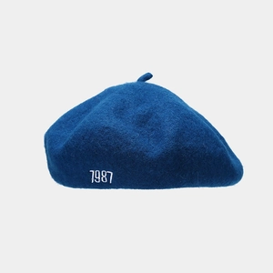 Detailed close-up of navy blue wool beret featuring high-quality 1987 white embroidery