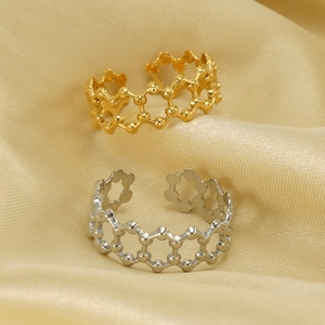Adjustable 18K gold and silver honeycomb open rings displayed on soft silk fabric