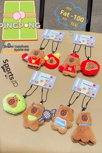 Close-up of cute plush capybara charms with sports gear and blue tags on beige texture