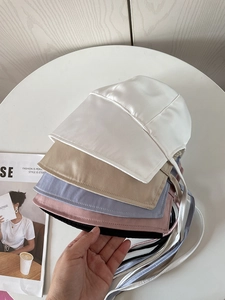 Detailed view of satin bucket hats with ties in white, beige, purple, pink and black