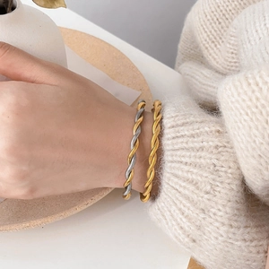 Elegant twisted rope bangle set in gold and silver finish worn with cozy knitwear