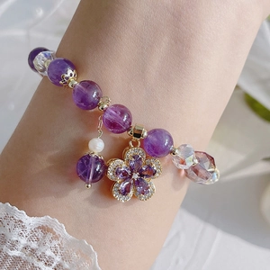 Detail of natural amethyst bracelet with zircon flower charm and pearl on wrist