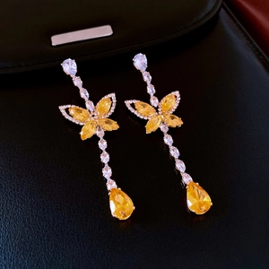 Détail de boucles d'oreilles pendantes papillon en argent avec zircons jaunes et taille poire