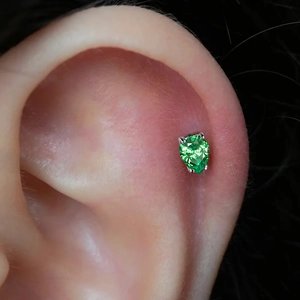 Close-up of a pear-cut emerald green zircon labret stud in a G23 titanium setting