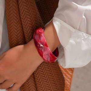 Macro shot of deep red marbled resin bangle featuring geometric faceted surfaces