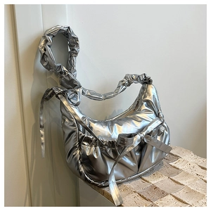 Detail of silver metallic puffer bag with bow accent and ruched shoulder strap texture