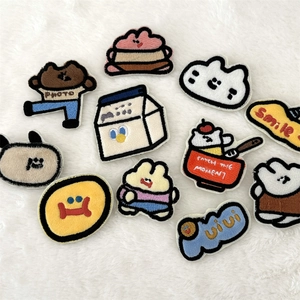 Flat lay of diverse cartoon embroidery patches with cute animals and smile typography