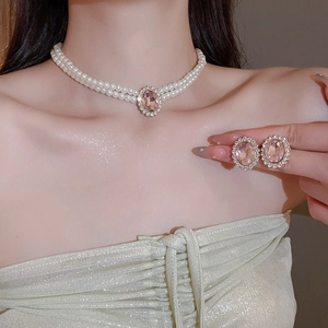 Detail view of double-layer pearl necklace with pink oval gemstone and matching earrings