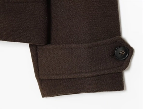 Détail de manche de manteau en laine marron foncé avec texture sergé et bouton noir