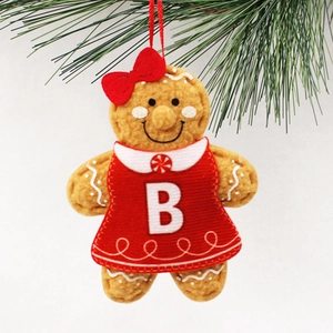 Gingerbread girl Christmas ornament with letter B and red bow on green pine needles