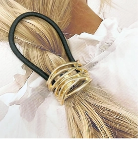 Close-up of golden geometric metal buckle on black elastic hair tie for ponytails
