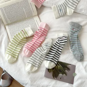 Close-up of pastel striped cotton socks with delicate letter embroidery on the cuffs