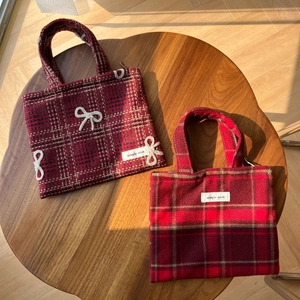 Gros plan de sacs à main en laine à carreaux rouges avec nœud blanc brodé et logo Simple Wish