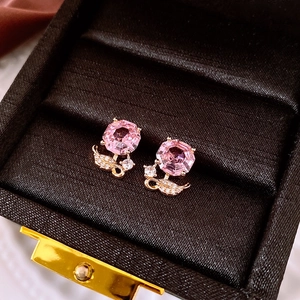 Gros plan de boucles d'oreilles en cristal rose avec feuilles de zircon dans un écrin sombre