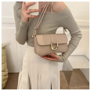 Minimalist beige baguette bag with golden horseshoe metal buckle and adjustable knotted strap
