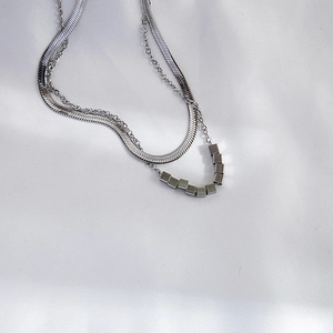 Detail of silver double-layered necklace with snake chain and geometric cube beads