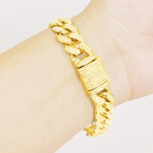 Gros plan d'un bracelet gourmette doré de 12 mm avec fermoir pavé brillant au poignet