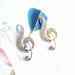 Macro view of gold and silver treble clef music note brooches with sparkling rhinestones