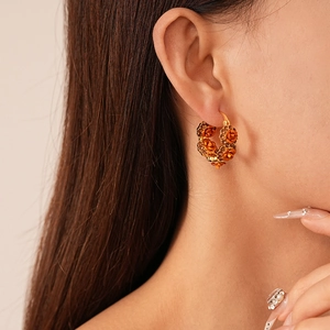 Detailed close-up of gold-plated flower hoop earring with orange roses and crystals