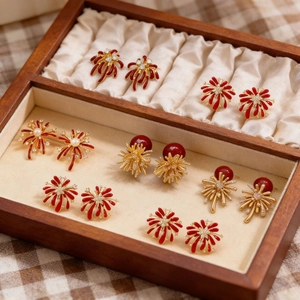 Macro shot of festive red enamel firework earrings with gold accents and pearls