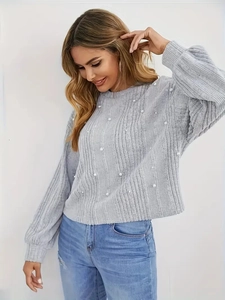 Gros plan sur un pull en maille côtelée grise avec d'élégantes perles blanches