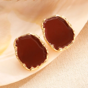 Macro shot of vintage irregular gold earrings with deep red enamel inlay on shell