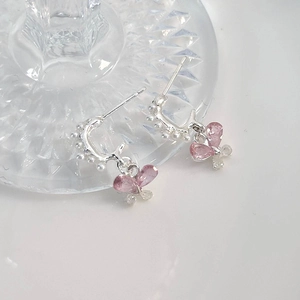 Makroaufnahme von rosa Kristall-Schmetterlingsohrringen mit Perlen und Zirkonia-Details