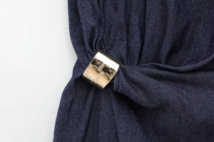 Gros plan sur le tissu denim bleu foncé avec boucles en métal doré poli sur la robe