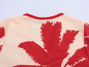 Detail of the round neckline with red braided trim and tropical leaf print pattern