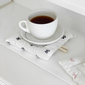 Close-up of bowknot pattern quilted coaster with cotton texture and brand tag