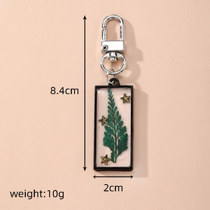 Detailed view of handmade rectangular resin keychain with green fern leaf and gold stars