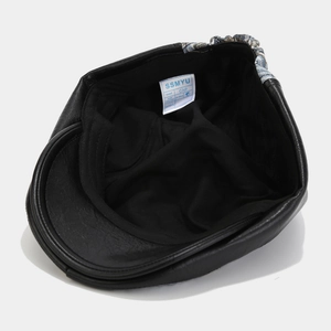 Detail shot of black faux leather hat featuring fabric lining and woven blue white trim