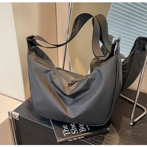 Detail view of a large black nylon crossbody dumpling bag in a cozy home interior setting