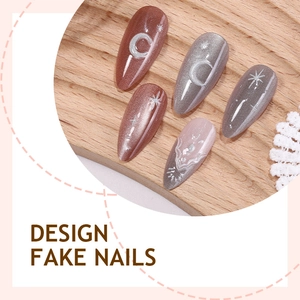 Cat-eye press-on nails with moon and star designs on a wooden tray with lace trim