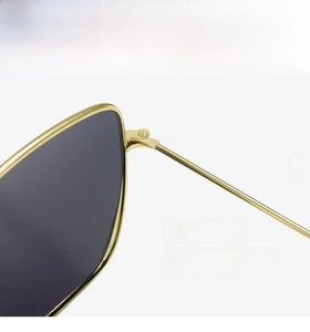 Macro view of sturdy metal hinge on square sunglasses with gold frame and dark lens