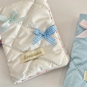 Close-up of quilted fabric passport covers with elegant bow details and brand label
