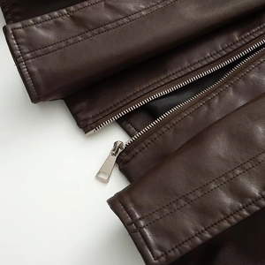 Détail de la fermeture éclair en métal et de la texture de la veste en cuir marron vintage