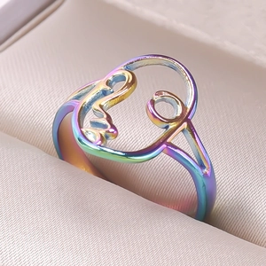 Close-up of abstract face design ring with rainbow plated finish in a jewelry box