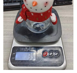 Detail view of a cute snowman candy jar being weighed on a digital scale at 3.9 oz