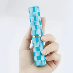 Detail of portable retractable makeup brush with blue checkerboard pattern and gold ring