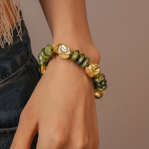 Detail of green acrylic beads and irregular golden metal beads on a beaded bracelet