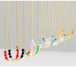 Detail of 18K gold plated necklaces featuring colorful faceted beads and white pearls