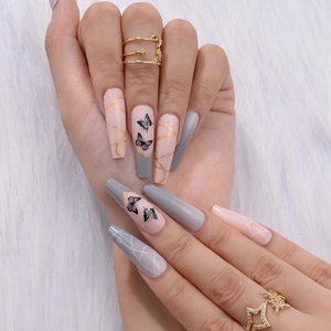 Detailed close-up of long coffin fake nails with black butterfly art and golden lines